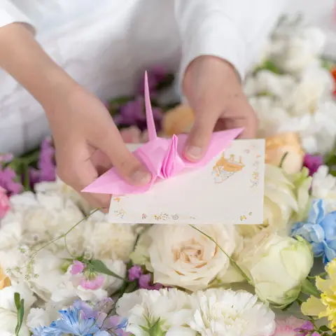 渋谷区民のわかりやすい火葬式の本物の花で作った生花祭壇を4人の参列者が見ている様子